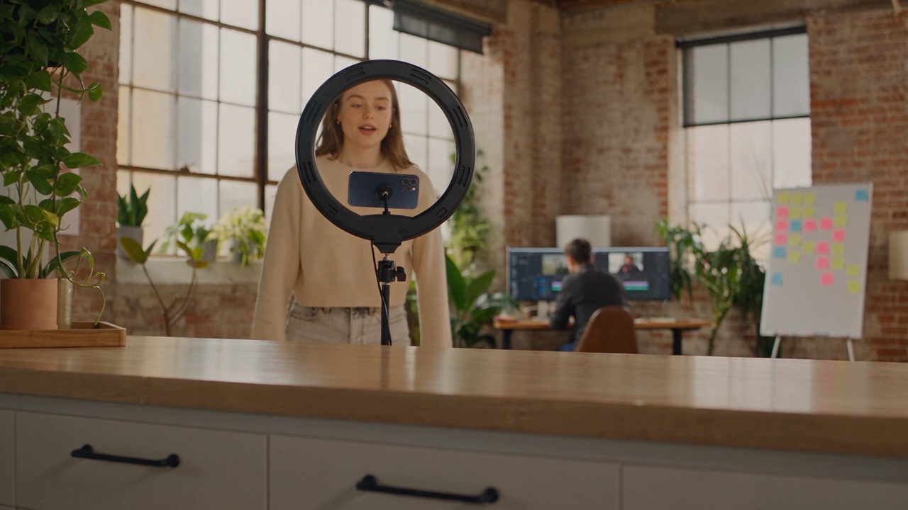 A creator mid-take, talking to a phone on a tripod inside a ring light